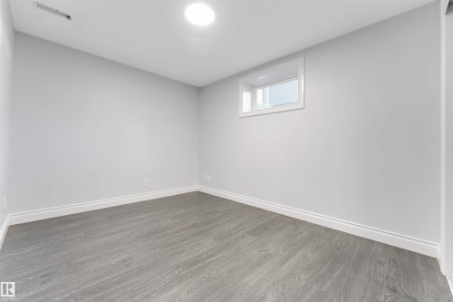 Room featuring light gray walls, wood-finish flooring, white baseboards, and a single window with white trim - 7419 33 Avenue Nw, Edmonton, AB - Indoor Photo Showing Other Room