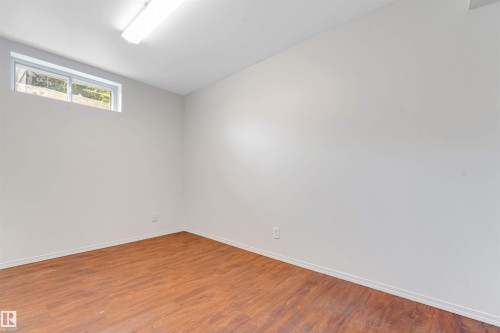 Spacious interior room with wood-finish flooring, light-toned walls, and a white ceiling - 7419 33 Avenue Nw, Edmonton, AB - Indoor Photo Showing Other Room
