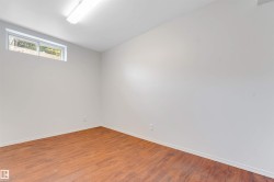 Spacious interior room with wood-finish flooring, light-toned walls, and a white ceiling - 