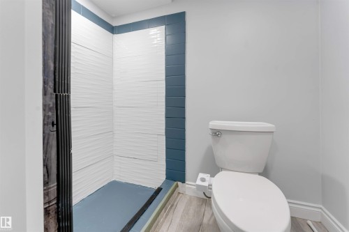 Bathroom featuring a walk-in shower with textured white tile walls and blue accent tiling - 7419 33 Avenue Nw, Edmonton, AB - Indoor Photo Showing Bathroom