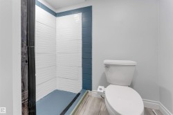 Bathroom featuring a walk-in shower with textured white tile walls and blue accent tiling - 