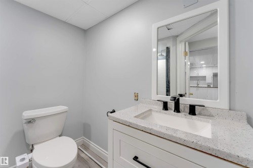 Bathroom featuring a white vanity with a speckled countertop, integrated sink, and matte black faucet - 7419 33 Avenue Nw, Edmonton, AB - Indoor Photo Showing Bathroom