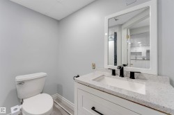 Bathroom featuring a white vanity with a speckled countertop, integrated sink, and matte black faucet - 