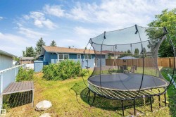 Expansive backyard featuring a partial privacy fence, mature trees, and a visible exterior of the property - 