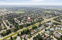 Expansive aerial view showcasing a residential neighborhood with detached homes, mature trees, and arterial roads - 
