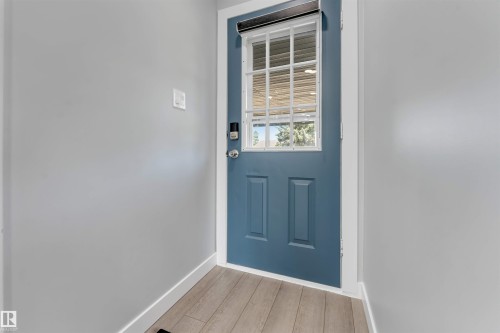Entrance door with upper window pane detailing and a digital lock - 7419 33 Avenue Nw, Edmonton, AB - Indoor Photo Showing Other Room