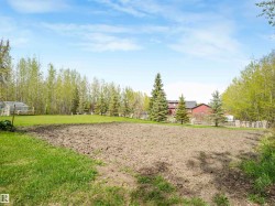 Expansive cleared land featuring cultivated soil and surrounding green lawn - 