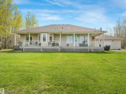 Expansive rear exterior featuring a covered deck, multiple large windows, and an attached garage - 