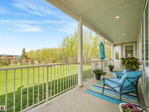 Covered concrete patio featuring recessed lighting, a white metal railing, and a verdant treeline backdrop - 16 Crystal Keys Crescent, Rural Wetaskiwin County, AB - Outdoor With Deck Patio Veranda With Exterior