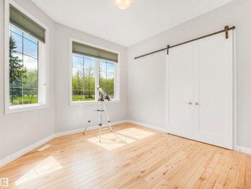 Light-filled room featuring wood-finish flooring, two large multi-pane windows, and a double barn door with bronze hardware - 16 Crystal Keys Crescent, Rural Wetaskiwin County, AB - Indoor Photo Showing Other Room