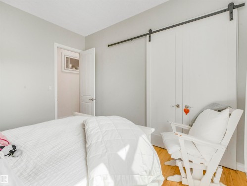 Light wood-finish flooring with a white door and a white barn door closet featuring a black sliding track - 16 Crystal Keys Crescent, Rural Wetaskiwin County, AB - Indoor Photo Showing Bedroom