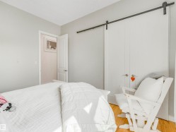 Light wood-finish flooring with a white door and a white barn door closet featuring a black sliding track - 
