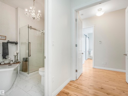 Bathroom featuring a freestanding soaking tub, glass-enclosed shower, white tile flooring, and a crystal chandelier - 16 Crystal Keys Crescent, Rural Wetaskiwin County, AB - Indoor Photo Showing Bathroom
