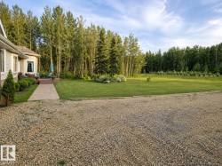 Spacious gravel driveway fronting a manicured lawn - 