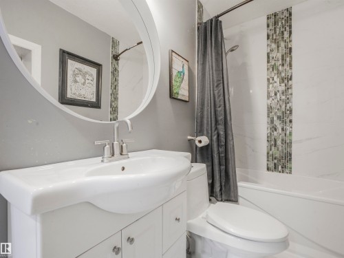 Contemporary bathroom featuring a white vanity with integrated sink, brushed nickel faucet, and an oval mirror - 16 Crystal Keys Crescent, Rural Wetaskiwin County, AB - Indoor Photo Showing Bathroom
