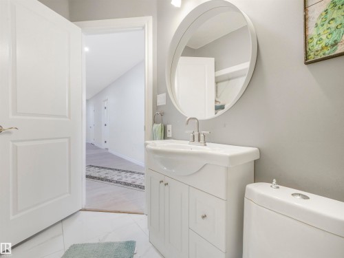 Bathroom featuring a white vanity with integrated sink, chrome faucet, and round mirror - 16 Crystal Keys Crescent, Rural Wetaskiwin County, AB - Indoor Photo Showing Bathroom