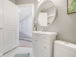 Bathroom featuring a white vanity with integrated sink, chrome faucet, and round mirror - 