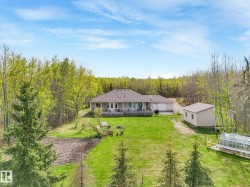 Expansive property featuring a ranch-style residence with a covered back patio, a detached two-car garage, and a separate outbuilding - 