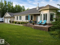 Expansive backyard featuring a manicured lawn, a multi-tiered deck, a distinct bay window structure, and a two-car garage - 