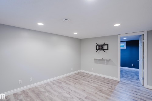 Spacious room featuring light gray walls, wood-finish flooring, recessed ceiling lighting, and white baseboards - 12431 81 Street Nw, Edmonton, AB - Indoor