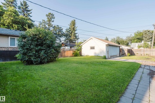Spacious backyard featuring a large lawn, mature shrubbery, a detached garage, and a paved walkway - 12431 81 Street Nw, Edmonton, AB - Outdoor