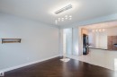 Open-concept space featuring dark wood-finish flooring and a contemporary linear chandelier with spherical pendants - 12431 81 Street Nw, Edmonton, AB  - Indoor Photo Showing Other Room 