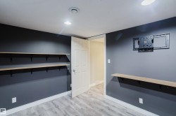 Room featuring light wood-finish flooring, dark gray walls with white trim, and recessed lighting - 