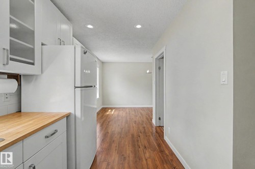 Kitchenette featuring white cabinetry with glass-front uppers, wood-finish countertops, and a white subway tile backsplash - 8823 130A Avenue Nw, Edmonton, AB - Indoor