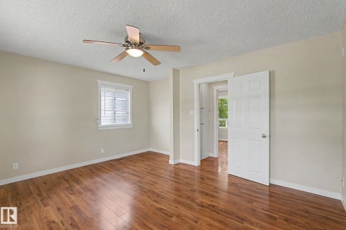 Spacious room featuring wood-finish flooring, a ceiling fan with integrated lighting, and a white paneled door - 8823 130A Avenue Nw, Edmonton, AB - Indoor Photo Showing Other Room
