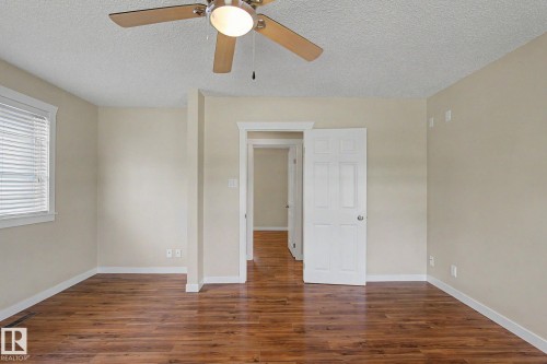 Spacious room featuring wood-finish flooring, neutral-toned walls, and a ceiling fan with integrated lighting - 8823 130A Avenue Nw, Edmonton, AB - Indoor Photo Showing Other Room