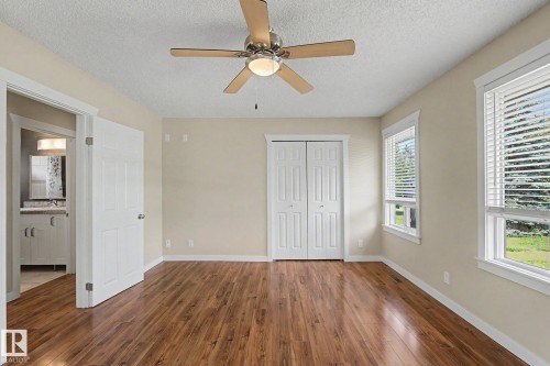 Spacious room featuring wood-finish flooring, two large windows with blinds, and a ceiling fan with integrated lighting - 8823 130A Avenue Nw, Edmonton, AB - Indoor Photo Showing Other Room