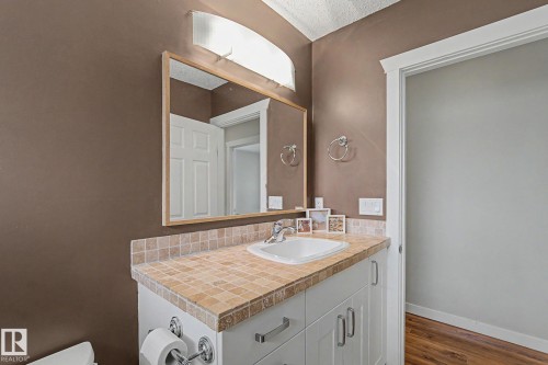 Bathroom vanity with a neutral tile countertop, integrated sink, and white cabinetry - 8823 130A Avenue Nw, Edmonton, AB - Indoor Photo Showing Bathroom