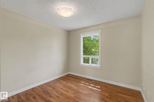 Room featuring wood-finish flooring, a double-paned window with white trim, and a flush-mount ceiling light fixture - 8823 130A Avenue Nw, Edmonton, AB - Indoor Photo Showing Other Room