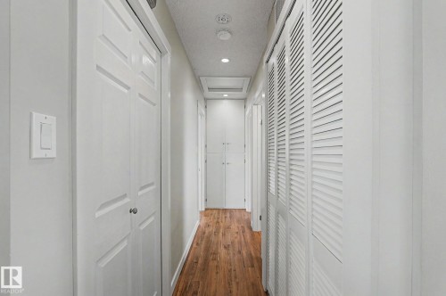Hallway featuring wood-finish flooring, recessed lighting, white panel doors, louvered closet doors, and white walls - 8823 130A Avenue Nw, Edmonton, AB - Indoor Photo Showing Other Room