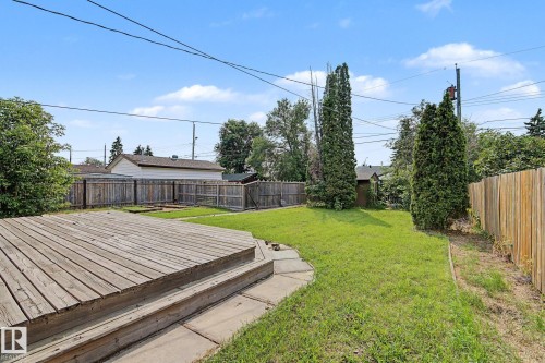 Expansive backyard featuring a large tiered wood deck, mature privacy trees, and a manicured lawn area - 8823 130A Avenue Nw, Edmonton, AB - Outdoor
