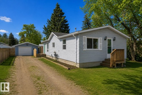 Light blue siding exterior with white window shutters and a wood-decked entry - 4712 49 Street, Calmar, AB - Outdoor