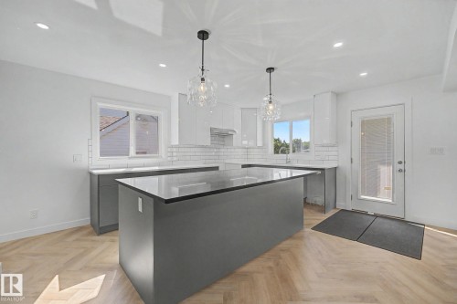 Modern kitchen with a substantial center island and sleek grey cabinetry - 10570 66 Avenue Nw, Edmonton, AB - Indoor Photo Showing Kitchen With Upgraded Kitchen