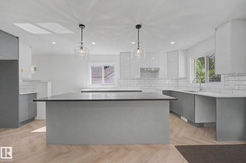 Contemporary kitchen featuring a dual-tone cabinetry scheme, two pendant light fixtures, recessed ceiling lighting, herringbone wood-finish flooring, and white subway tile backsplash - 10570 66 Avenue Nw, Edmonton, AB - Indoor Photo Showing Kitchen With Upgraded Kitchen