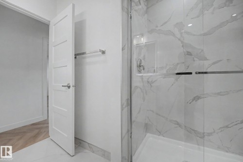 Walk-in shower with clear glass enclosure, a built-in shelf, and a polished chrome fixture - 10570 66 Avenue Nw, Edmonton, AB - Indoor Photo Showing Bathroom