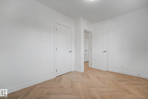 Room featuring herringbone wood-finish flooring, white baseboards, and white walls - 10570 66 Avenue Nw, Edmonton, AB - Indoor Photo Showing Other Room