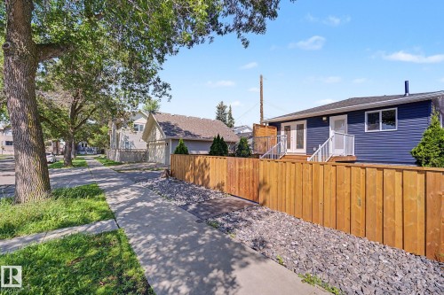Dark blue exterior siding with a wood privacy fence, featuring a raised deck with white railings - 10570 66 Avenue Nw, Edmonton, AB - Outdoor