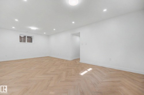 Spacious room featuring herringbone wood-finish flooring, recessed lighting, and a white baseboard trim - 10570 66 Avenue Nw, Edmonton, AB - Indoor