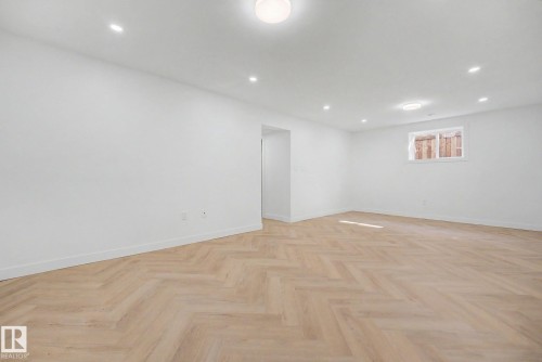 Spacious room featuring herringbone wood-finish flooring, recessed lighting, a flush mount ceiling fixture, and a single window with white trim - 10570 66 Avenue Nw, Edmonton, AB - Indoor Photo Showing Other Room