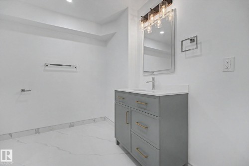 Contemporary bathroom featuring a gray vanity with gold-tone hardware, white countertop, and integrated sink - 10570 66 Avenue Nw, Edmonton, AB - Indoor Photo Showing Bathroom