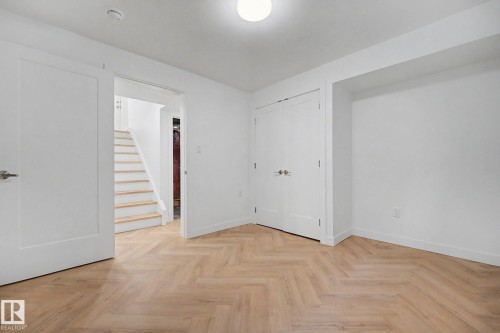 Light wood-finish flooring in a herringbone pattern - 10570 66 Avenue Nw, Edmonton, AB - Indoor Photo Showing Other Room