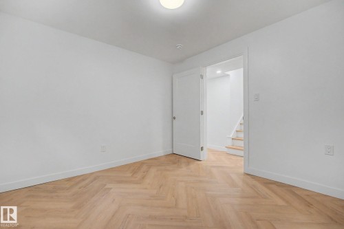 Room featuring light wood-finish herringbone flooring, white walls, and bright overhead lighting - 10570 66 Avenue Nw, Edmonton, AB - Indoor Photo Showing Other Room