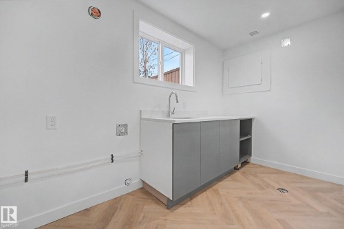 Utility space featuring light wood-finish herringbone flooring, a white countertop with an undermount sink, and gray cabinetry with open shelving - 10570 66 Avenue Nw, Edmonton, AB - Indoor Photo Showing Other Room