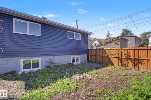 Rear exterior featuring blue horizontal siding, white trim windows, and a wood privacy fence - 10570 66 Avenue Nw, Edmonton, AB - Outdoor With Exterior