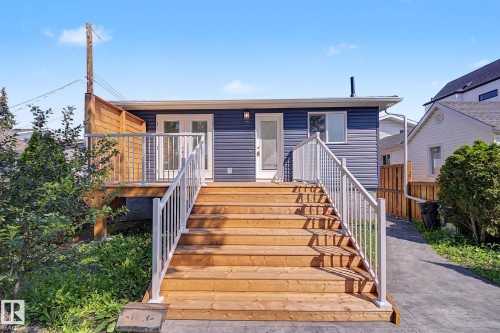 Rear exterior featuring dark blue horizontal siding and a wood deck - 10570 66 Avenue Nw, Edmonton, AB - Outdoor With Deck Patio Veranda