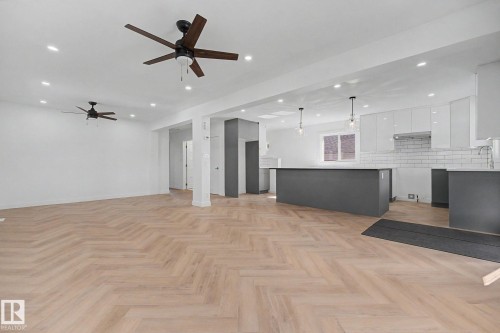 Open-concept living space featuring light wood-finish herringbone flooring, recessed lighting, and dual ceiling fans - 10570 66 Avenue Nw, Edmonton, AB - Indoor